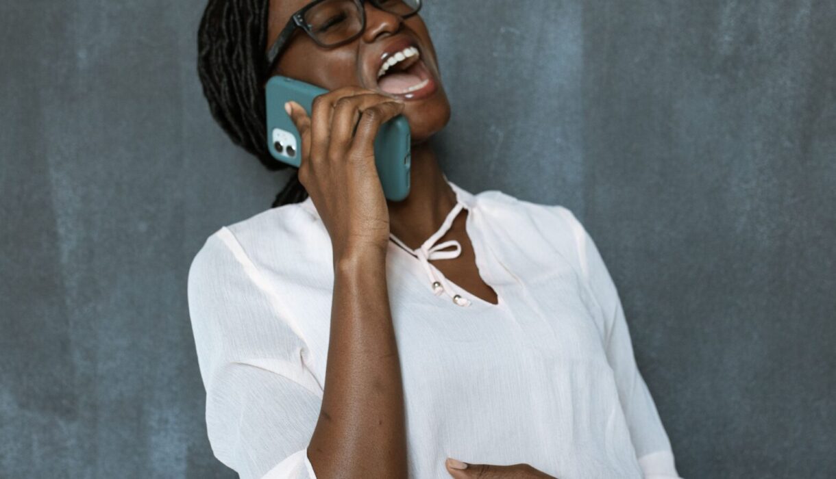 Woman laughing joyfully while talking on her smartphone