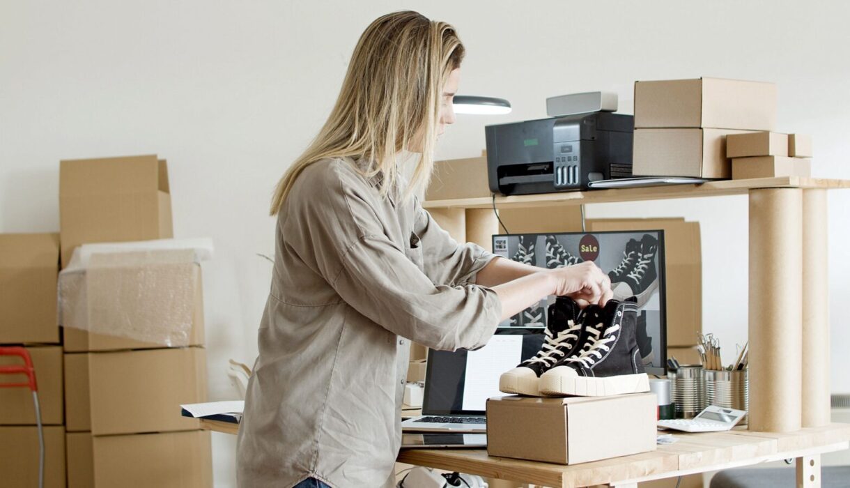 Woman placing a product into a cardboard box for shipping