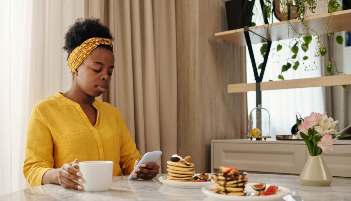 Woman using her smartphone while having breakfast at a cafe