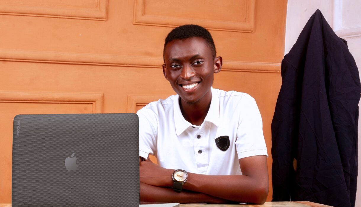 Young African man smiling at a desk with a laptop in an office setting