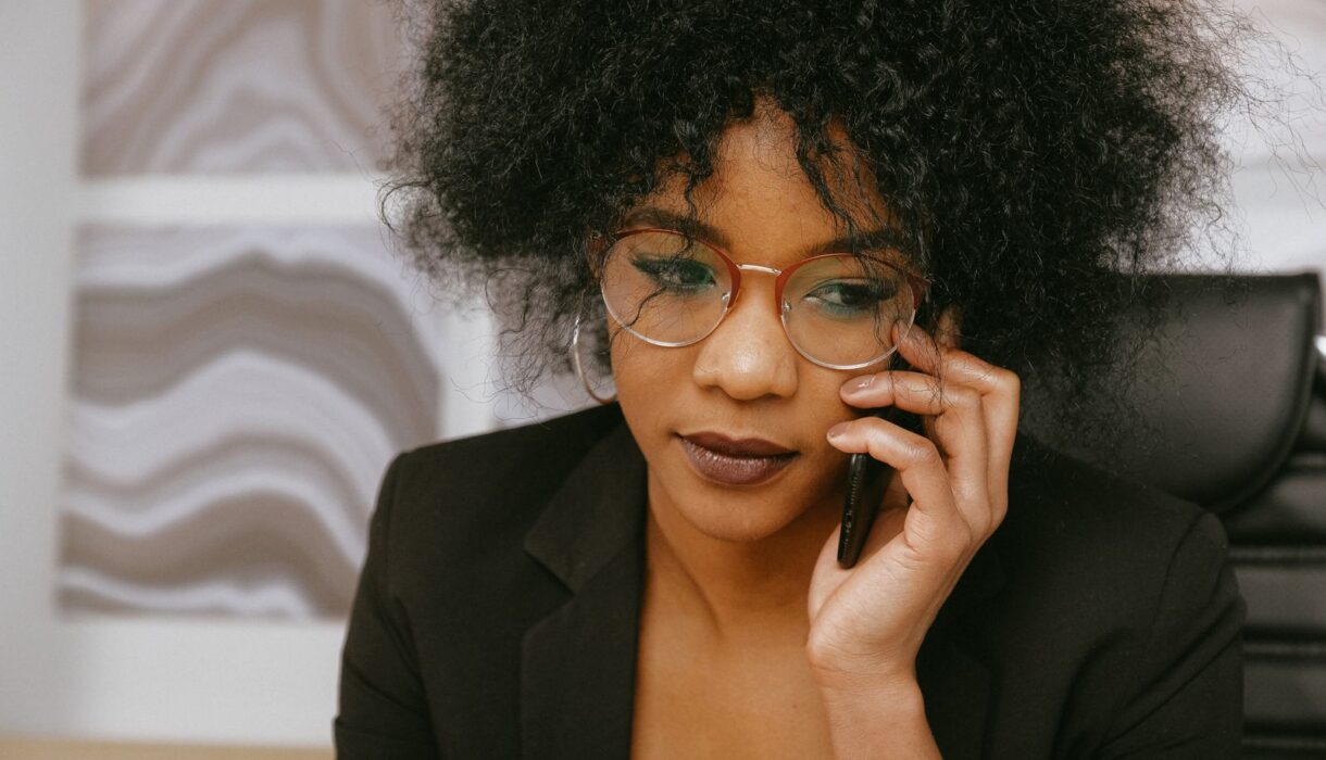 Businesswoman in a black blazer talking on the phone at her desk