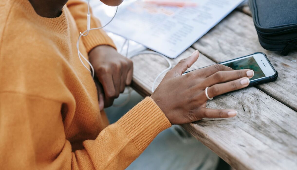 Woman using a smartphone at a wooden table to check her accounts