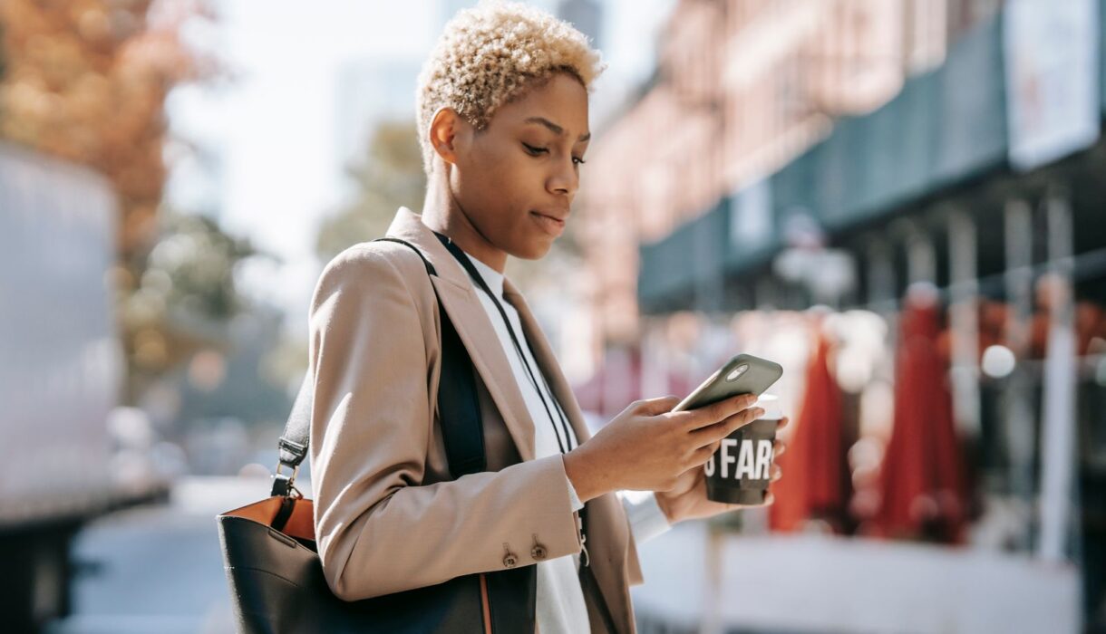 Woman concentrating while typing on her smartphone outdoors